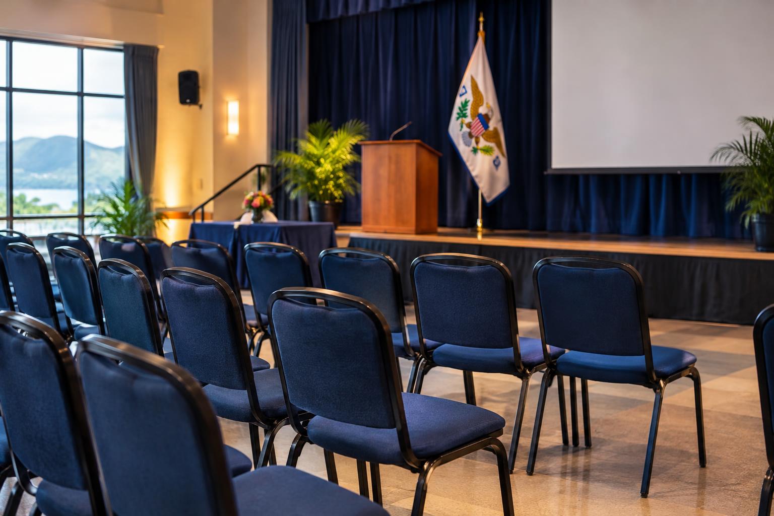 A welcoming school auditorium or community center interior with empty chairs arranged for a workshop, soft lighting, US Virgin Islands flag visible in the background, suggesting an educational or support session